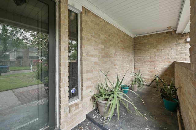 doorway to property with a porch and brick siding