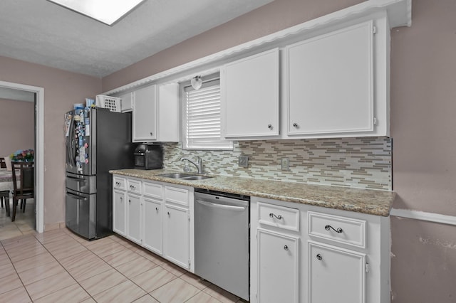 kitchen with decorative backsplash, a sink, light tile patterned floors, white cabinets, and stainless steel appliances