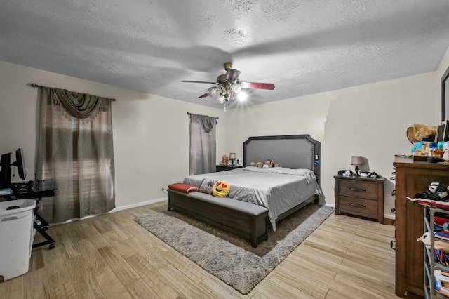 bedroom with a textured ceiling, ceiling fan, baseboards, and wood finished floors