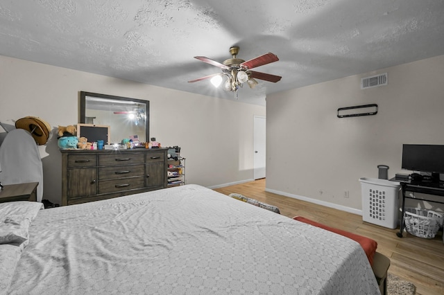 bedroom with visible vents, a textured ceiling, and wood finished floors