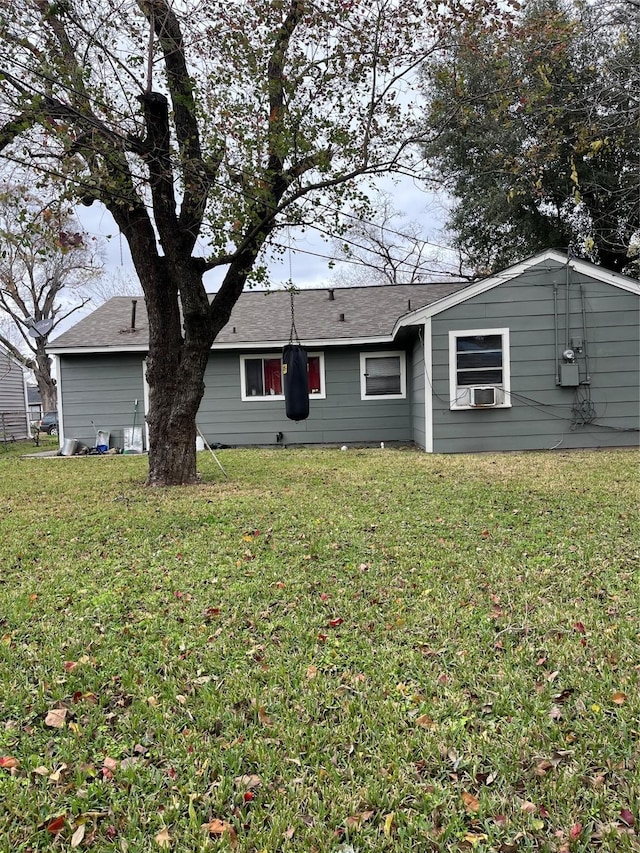 rear view of house with roof with shingles, a yard, and cooling unit