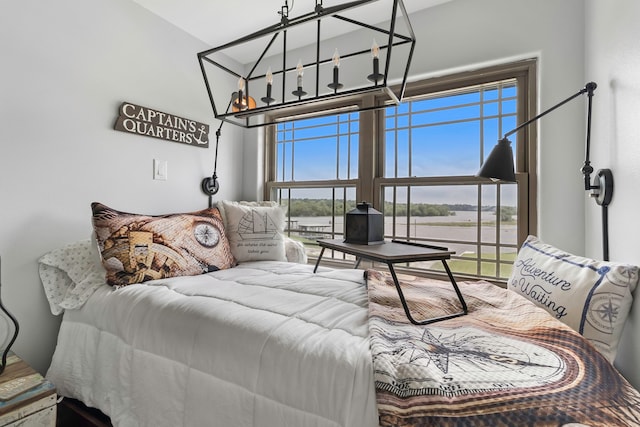 bedroom featuring a water view and a notable chandelier