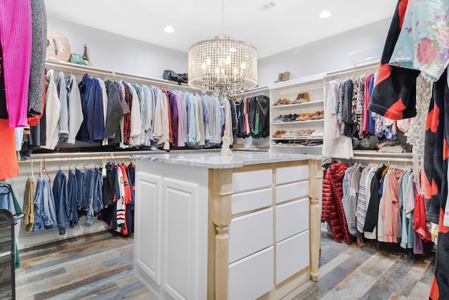 walk in closet featuring an inviting chandelier, wood finished floors, and visible vents