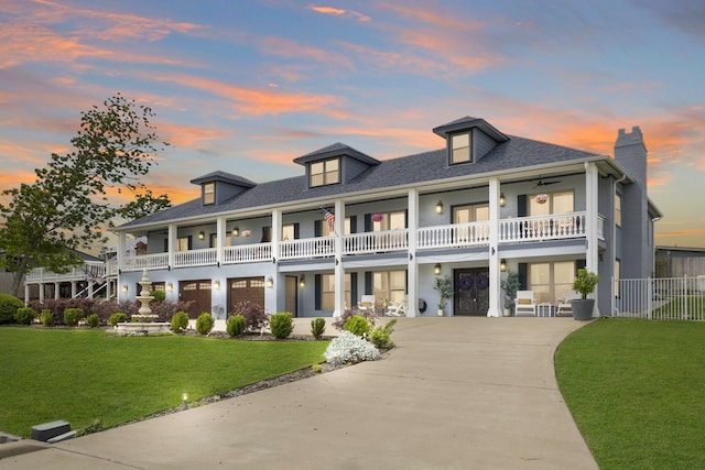 exterior space with driveway, a chimney, a lawn, fence, and a balcony