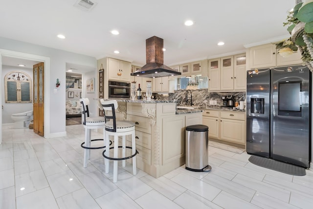 kitchen featuring visible vents, oven, island range hood, cream cabinets, and stainless steel fridge with ice dispenser