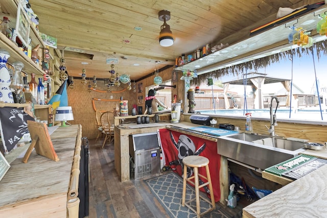 kitchen featuring a sink, wood ceiling, hardwood / wood-style flooring, and wooden walls