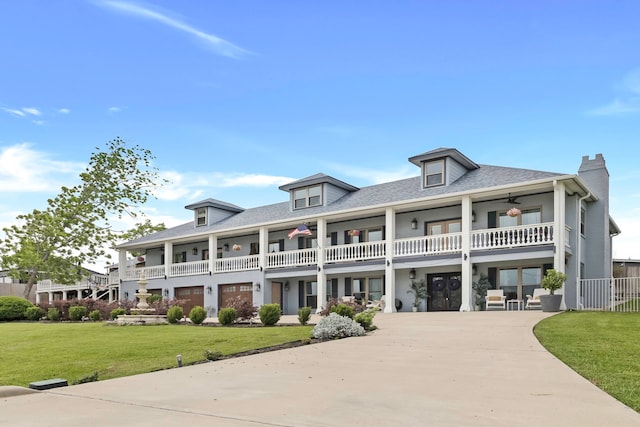 view of front of house featuring a balcony, a shingled roof, driveway, and a front yard