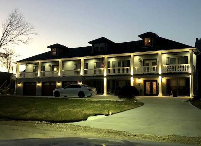 view of front of house featuring a yard, driveway, french doors, and a balcony