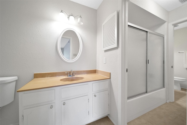 bathroom with vanity, enclosed tub / shower combo, and toilet