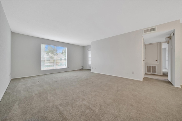 empty room featuring baseboards, light colored carpet, and visible vents