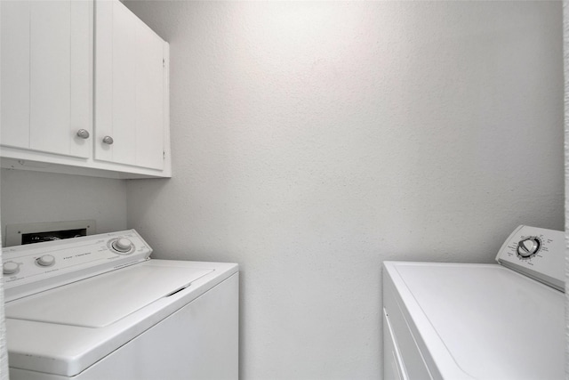 clothes washing area with cabinet space and independent washer and dryer