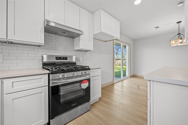kitchen featuring exhaust hood, stainless steel range with gas stovetop, light countertops, white cabinets, and light wood-style floors