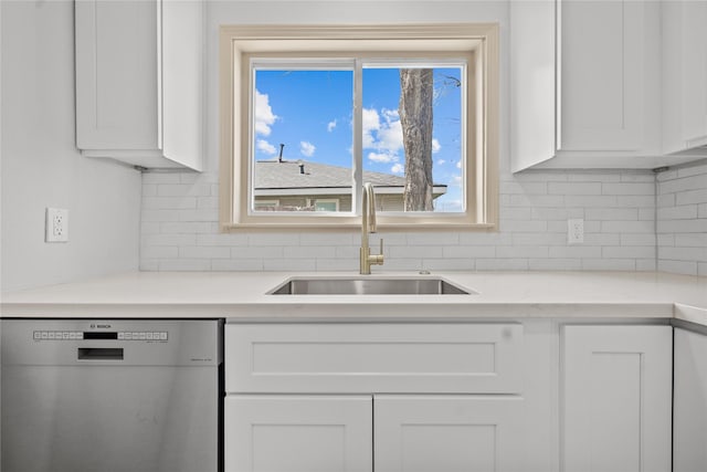 kitchen featuring a sink, dishwasher, light countertops, white cabinetry, and backsplash