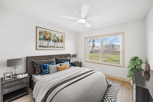bedroom featuring a ceiling fan, baseboards, and light wood-style flooring