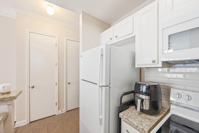 kitchen featuring crown molding, light stone countertops, light tile patterned floors, white cabinets, and white appliances
