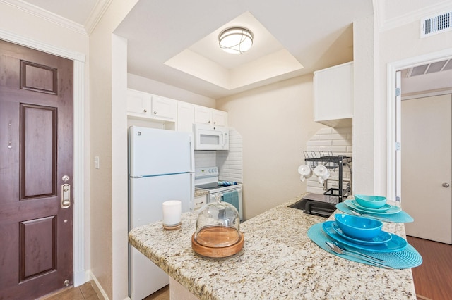 kitchen with visible vents, decorative backsplash, white appliances, white cabinets, and light stone counters