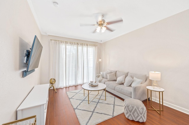 living area featuring crown molding, baseboards, a ceiling fan, and wood finished floors