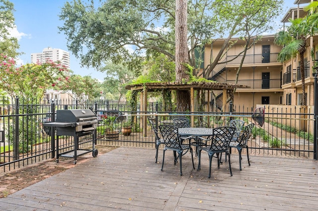 deck featuring outdoor dining area, fence, and grilling area