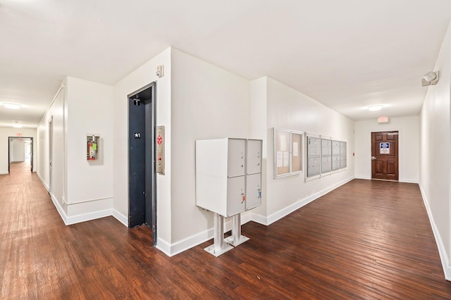 entryway featuring baseboards, dark wood finished floors, and mail area