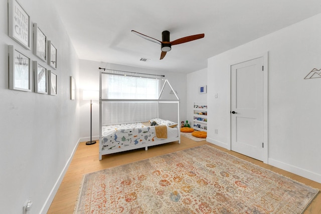 bedroom featuring baseboards, a ceiling fan, wood finished floors, and visible vents