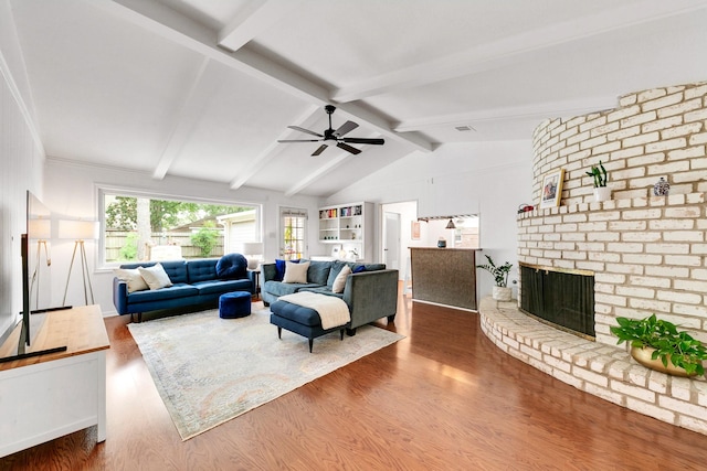 living room featuring a fireplace, a ceiling fan, vaulted ceiling with beams, and wood finished floors