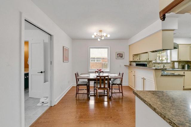 dining room featuring baseboards, plenty of natural light, light wood-type flooring, and a chandelier