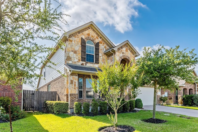 traditional-style home with driveway, a front yard, brick siding, fence, and stone siding