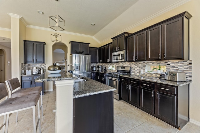 kitchen featuring arched walkways, tasteful backsplash, a sink, dark stone counters, and stainless steel appliances