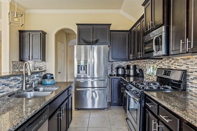 kitchen with crown molding, arched walkways, a sink, appliances with stainless steel finishes, and backsplash