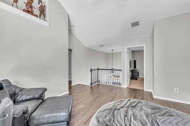 living area featuring baseboards, vaulted ceiling, wood finished floors, and visible vents