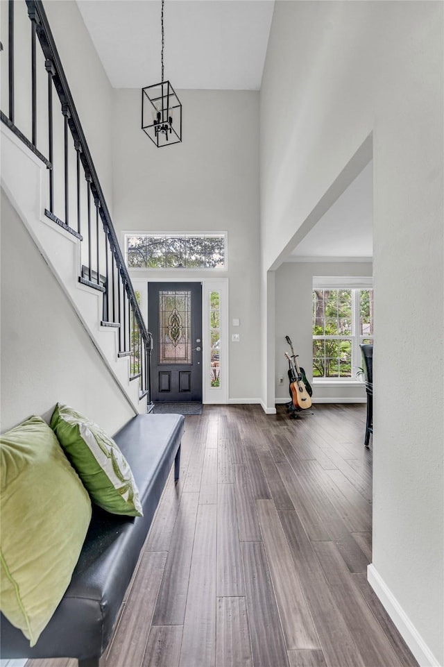foyer with a towering ceiling, stairway, baseboards, dark wood-style floors, and a notable chandelier
