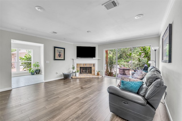 living room featuring crown molding, plenty of natural light, a brick fireplace, and visible vents