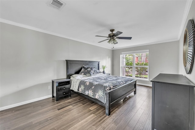 bedroom featuring crown molding, visible vents, wood finished floors, baseboards, and ceiling fan