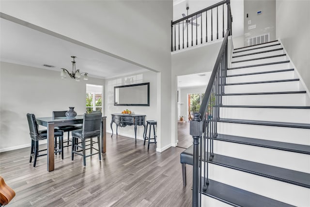 interior space featuring stairs, a notable chandelier, plenty of natural light, and wood finished floors
