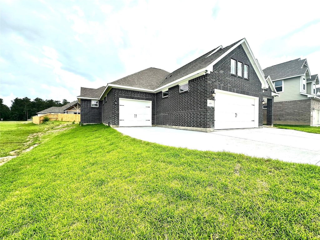 view of side of home featuring brick siding, a garage, a yard, and concrete driveway
