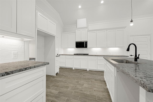 123 Big Spring Dr, Anahuac, TX 77514 - kitchen with stainless steel microwave, a sink, crown molding, backsplash, and white cabinetry