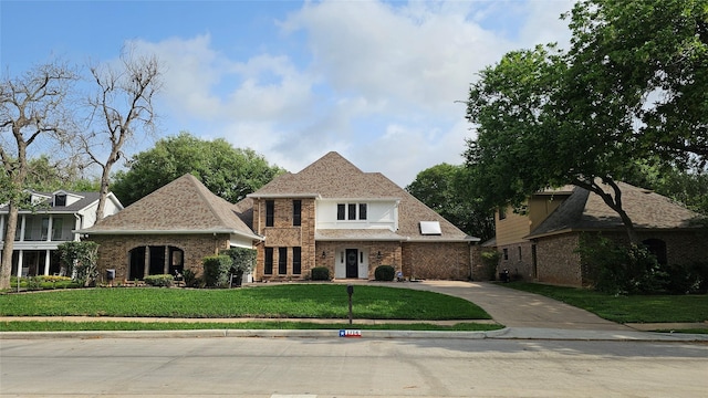 french country style house featuring driveway, a front lawn, and brick siding