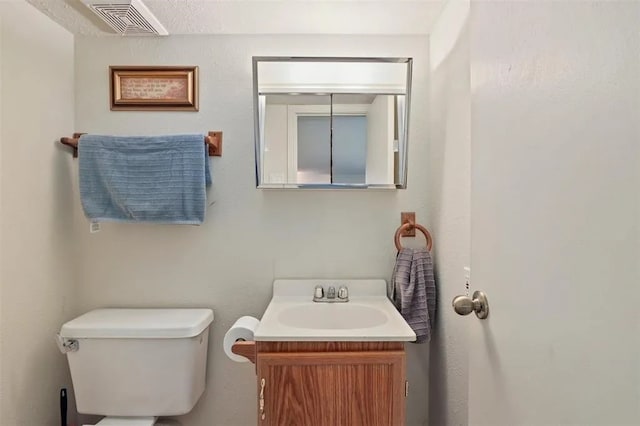 half bath featuring toilet, visible vents, and vanity