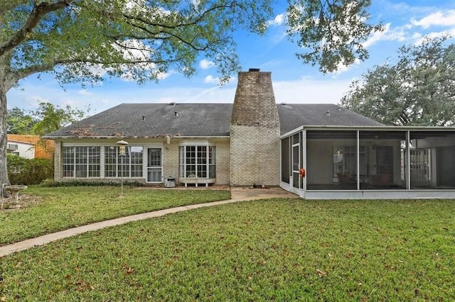 back of property featuring a sunroom, a yard, and a chimney