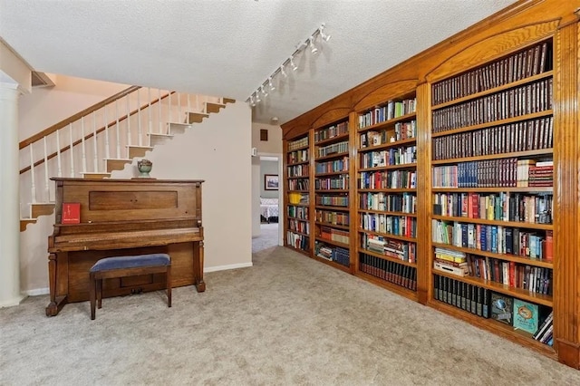 sitting room with carpet flooring, rail lighting, a textured ceiling, and stairs