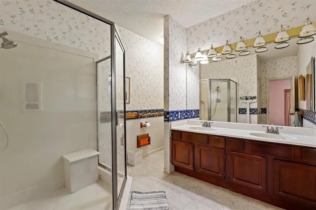 full bath with a sink, a shower stall, wallpapered walls, and double vanity