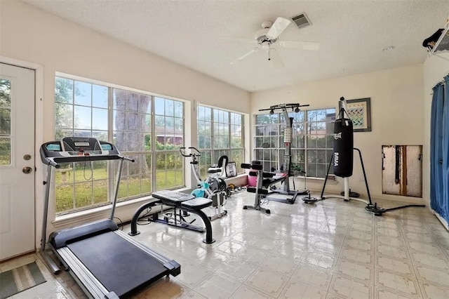 exercise room with baseboards, ceiling fan, visible vents, and a healthy amount of sunlight