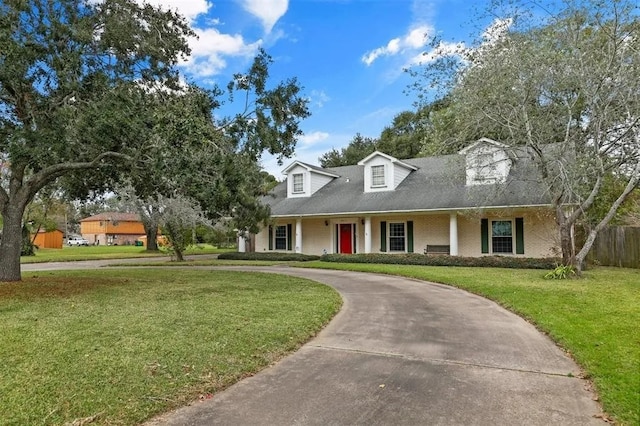 cape cod-style house with brick siding, fence, a front yard, and curved driveway