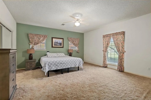 bedroom with carpet floors, a textured ceiling, and multiple windows