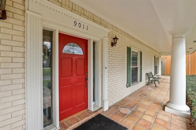 entrance to property featuring covered porch and brick siding