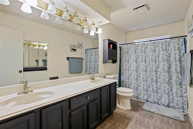 bathroom featuring toilet, a textured ceiling, visible vents, and a sink