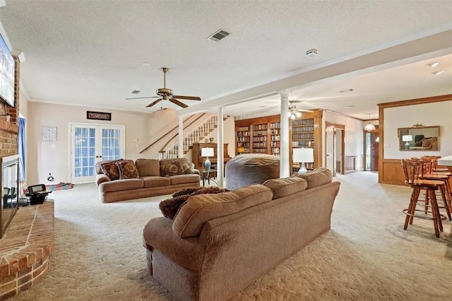 carpeted living area with visible vents, a ceiling fan, crown molding, and a fireplace