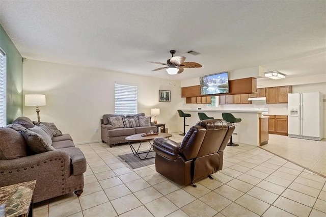 living room with ceiling fan, light tile patterned flooring, and visible vents
