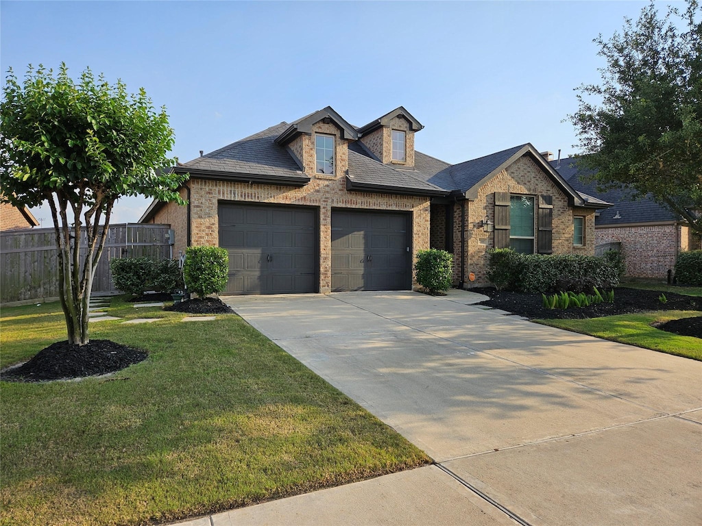 view of front of property with an attached garage, a front yard, and brick siding
