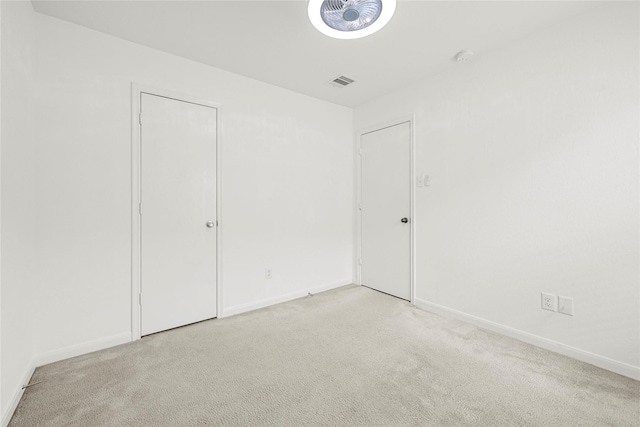 unfurnished bedroom featuring light colored carpet, baseboards, and visible vents
